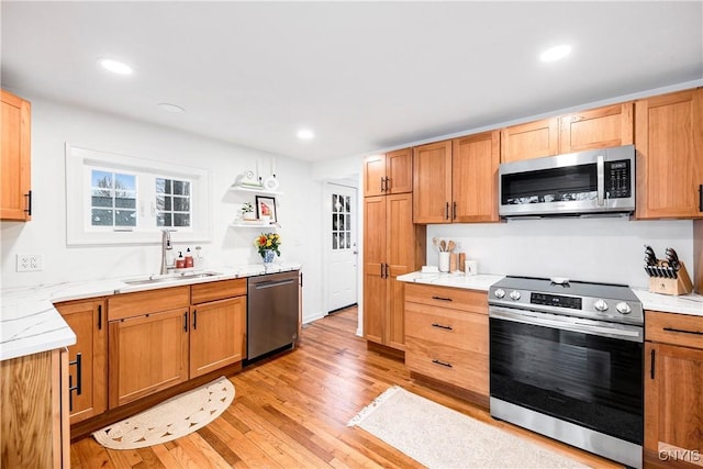 kitchen featuring light stone counters, appliances with stainless steel finishes, light hardwood / wood-style flooring, and sink