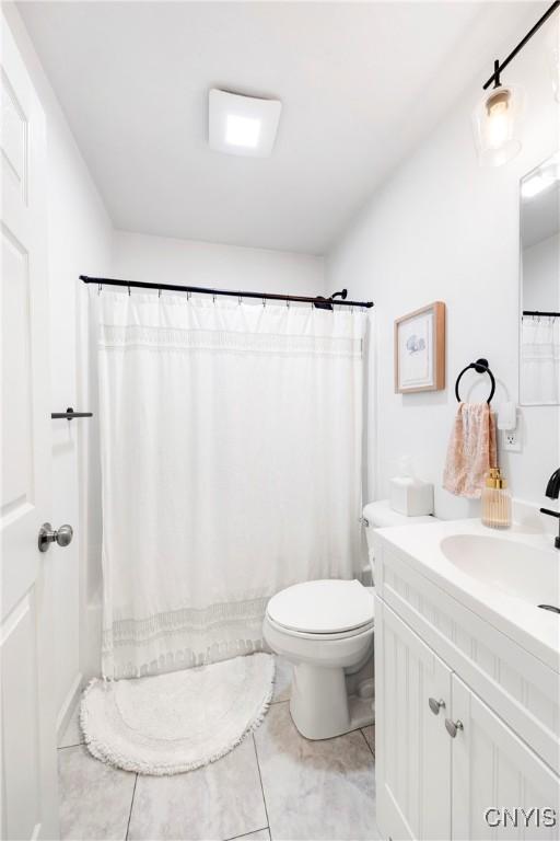 bathroom featuring toilet, vanity, tile patterned floors, and curtained shower