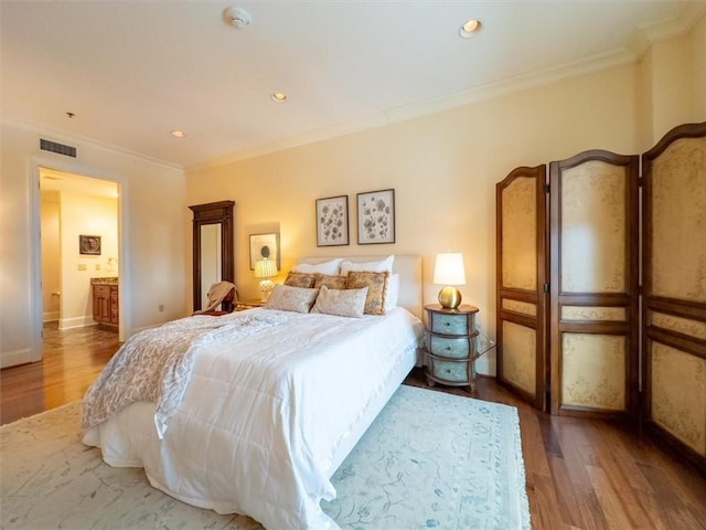 bedroom with hardwood / wood-style floors, connected bathroom, and ornamental molding