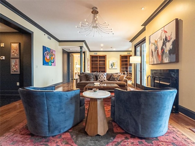 living room with a fireplace, ornamental molding, an inviting chandelier, and dark wood-type flooring