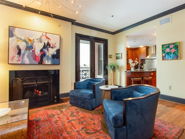 living area with dark wood-type flooring, crown molding, and sink