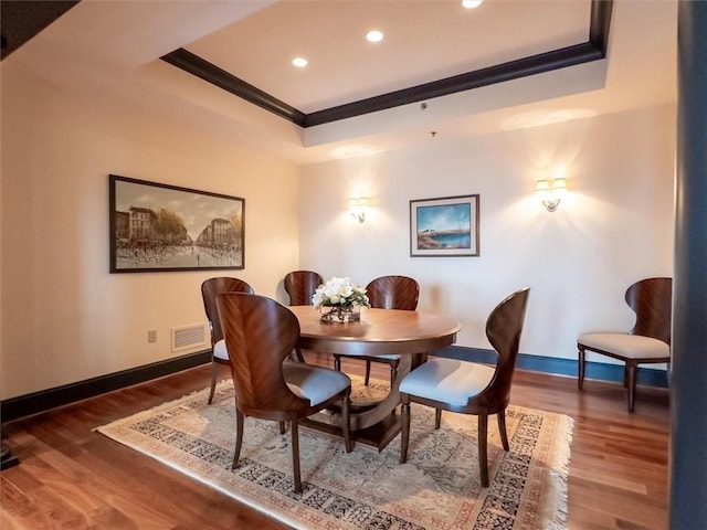 dining area featuring hardwood / wood-style flooring, ornamental molding, and a tray ceiling