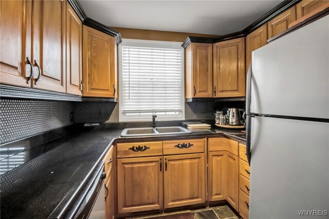 kitchen featuring sink, dishwashing machine, tasteful backsplash, and stainless steel fridge