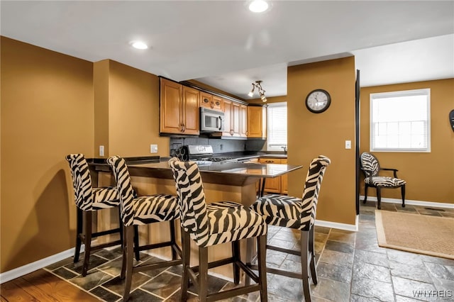 kitchen with stainless steel appliances, a kitchen breakfast bar, and kitchen peninsula