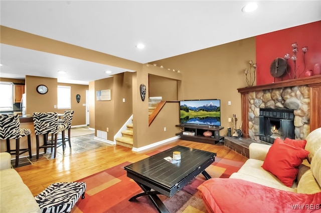 living room with a stone fireplace and hardwood / wood-style flooring