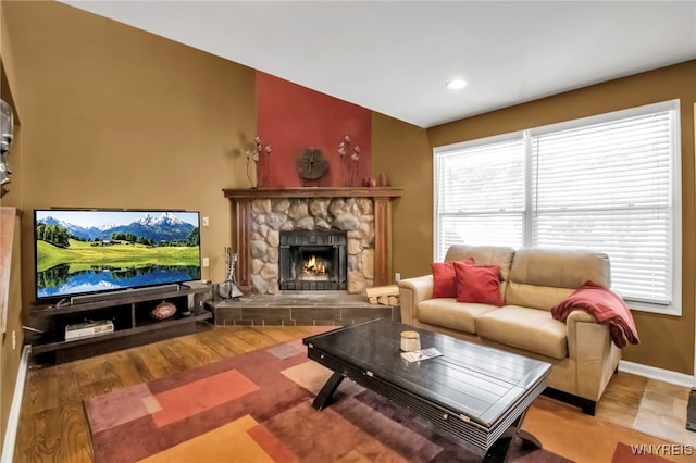 living room with light hardwood / wood-style floors and a stone fireplace