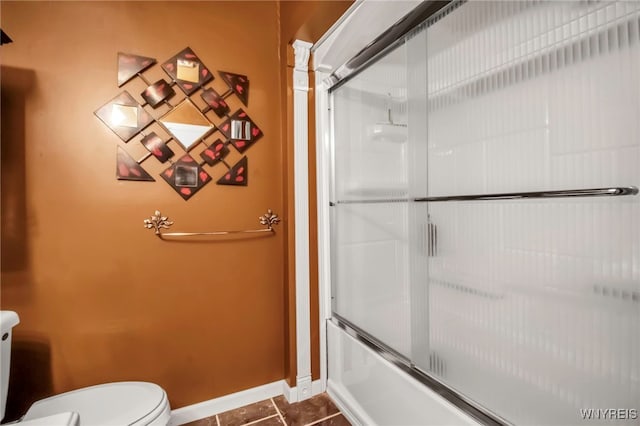 bathroom featuring tile patterned flooring, shower / bath combination with glass door, and toilet