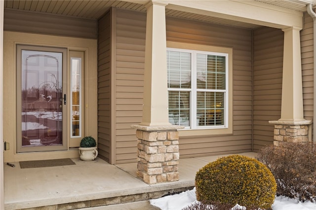 snow covered property entrance featuring a porch