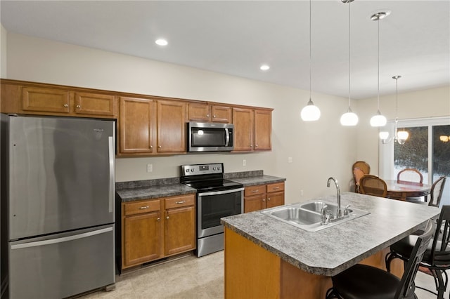 kitchen featuring a kitchen breakfast bar, stainless steel appliances, an island with sink, sink, and decorative light fixtures