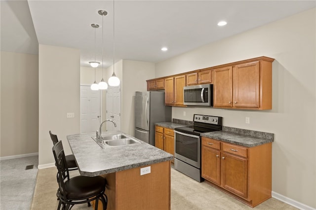 kitchen with a kitchen breakfast bar, a kitchen island with sink, appliances with stainless steel finishes, hanging light fixtures, and sink