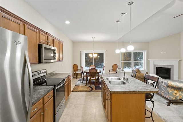 kitchen with pendant lighting, stainless steel appliances, an island with sink, a breakfast bar area, and sink