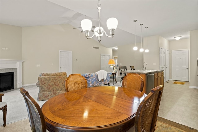 tiled dining area with a tiled fireplace, a chandelier, vaulted ceiling, and sink