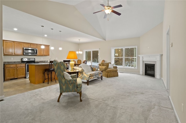 carpeted living room with ceiling fan with notable chandelier and high vaulted ceiling