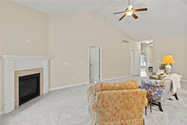 carpeted living room featuring a tile fireplace, high vaulted ceiling, and ceiling fan