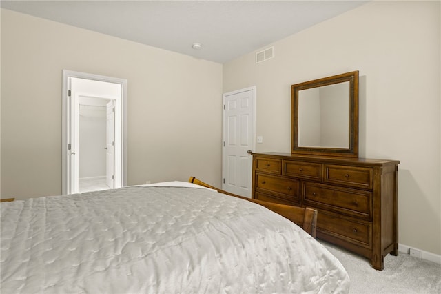 bedroom with a walk in closet, light colored carpet, and a closet