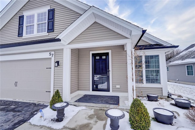 snow covered property entrance featuring a garage