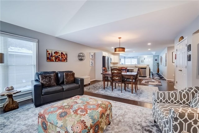 living room featuring sink, wood-type flooring, and lofted ceiling