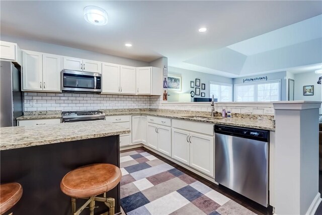 kitchen featuring white cabinets, appliances with stainless steel finishes, and a kitchen breakfast bar