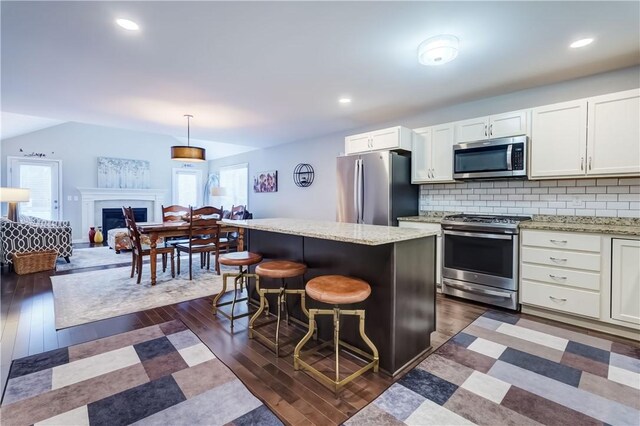 kitchen with a kitchen bar, stainless steel appliances, decorative backsplash, decorative light fixtures, and a kitchen island