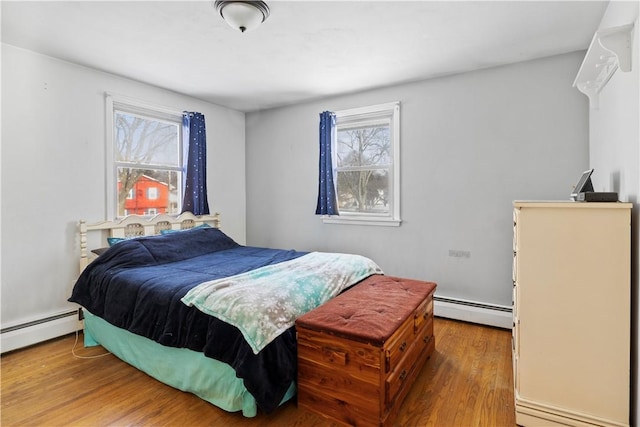 bedroom with hardwood / wood-style floors, multiple windows, and baseboard heating