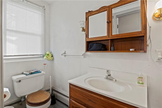 bathroom featuring toilet, vanity, and a baseboard heating unit