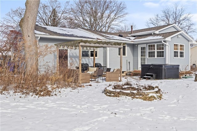 snow covered house featuring a hot tub and a pergola