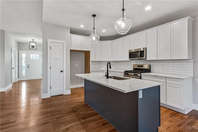 kitchen with stainless steel appliances, a kitchen island with sink, and white cabinetry