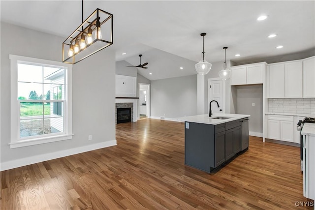 kitchen with hanging light fixtures, a center island with sink, decorative backsplash, white cabinets, and sink