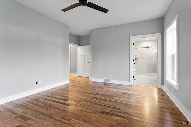 unfurnished bedroom featuring hardwood / wood-style floors, ceiling fan, and connected bathroom