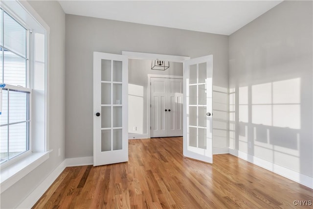 spare room with french doors and light hardwood / wood-style flooring