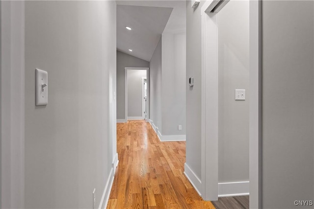 corridor featuring lofted ceiling, light wood-type flooring, and a barn door