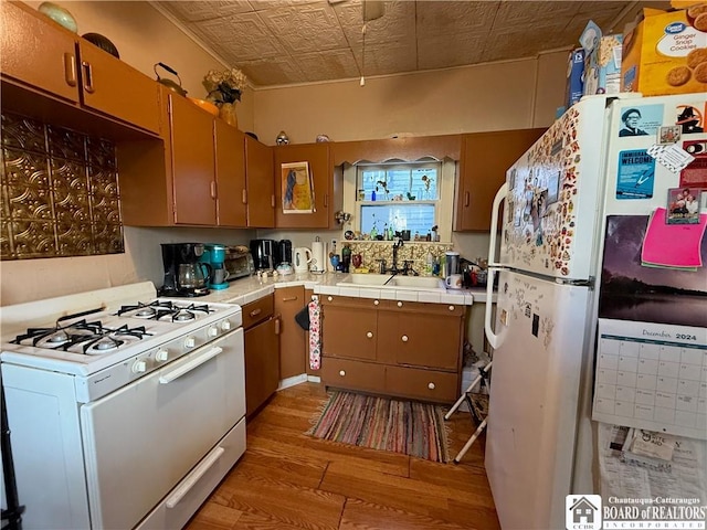 kitchen featuring white appliances, hardwood / wood-style floors, sink, and tile counters