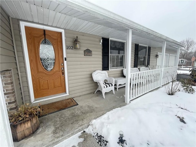 snow covered property entrance with a porch