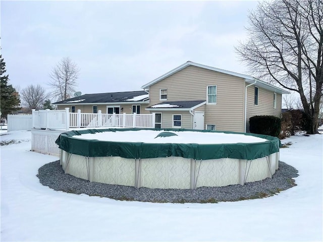 snow covered back of property with a pool side deck