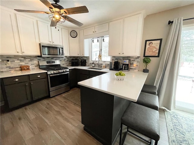 kitchen with sink, kitchen peninsula, white cabinets, and stainless steel appliances