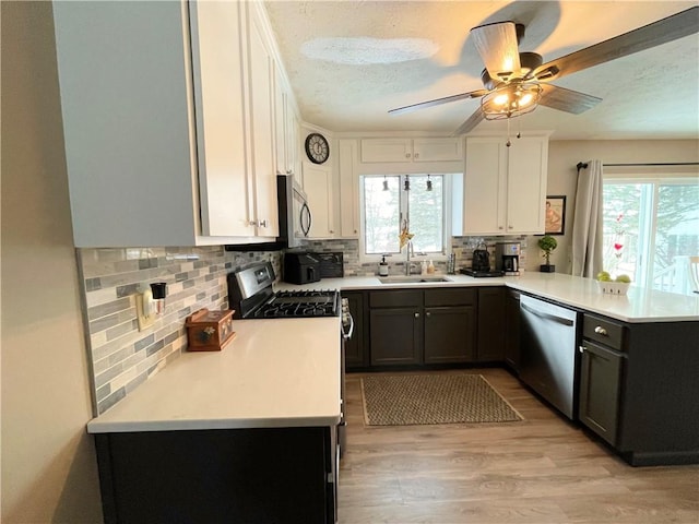 kitchen with kitchen peninsula, stainless steel appliances, backsplash, white cabinets, and sink