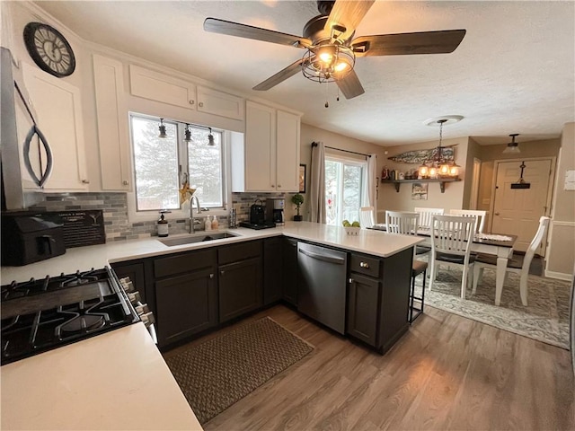 kitchen featuring decorative light fixtures, kitchen peninsula, sink, appliances with stainless steel finishes, and white cabinets