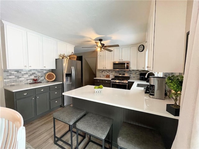 kitchen featuring kitchen peninsula, gray cabinets, appliances with stainless steel finishes, white cabinets, and sink