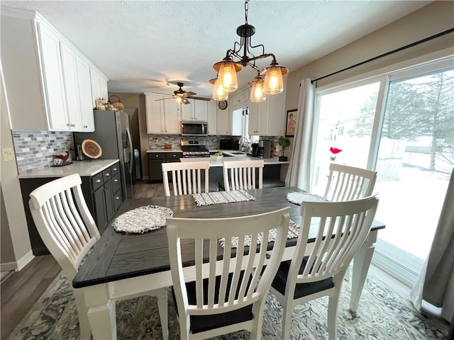 dining room featuring dark hardwood / wood-style flooring, sink, and ceiling fan with notable chandelier