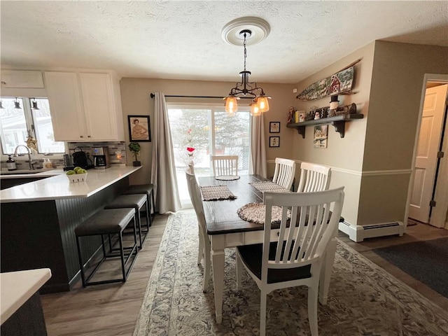 dining area featuring a notable chandelier, sink, a textured ceiling, and hardwood / wood-style flooring