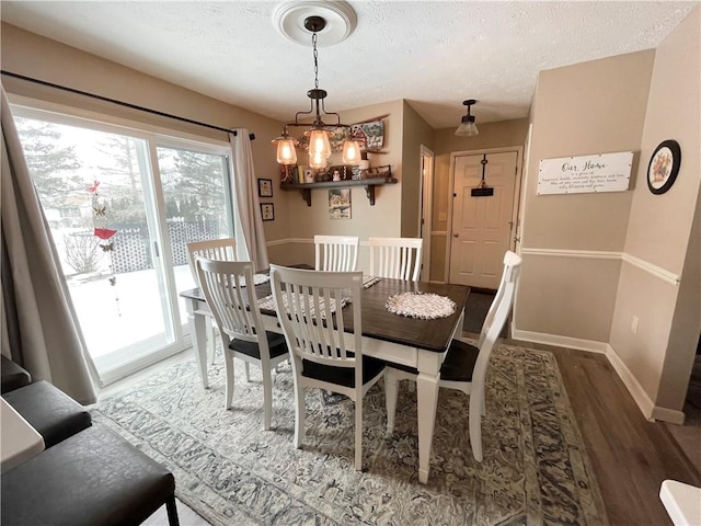 dining space with hardwood / wood-style floors, a textured ceiling, and a notable chandelier