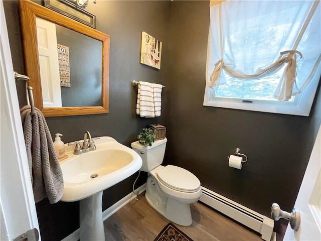 bathroom featuring baseboard heating, wood-type flooring, toilet, and sink