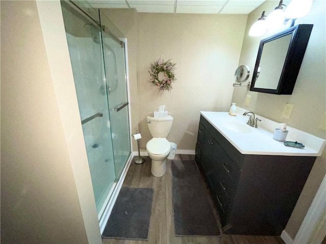 bathroom featuring toilet, hardwood / wood-style floors, an enclosed shower, a drop ceiling, and vanity