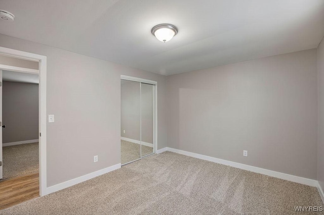 unfurnished bedroom featuring light colored carpet and a closet