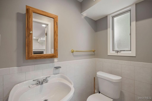 bathroom with toilet, tile walls, and sink