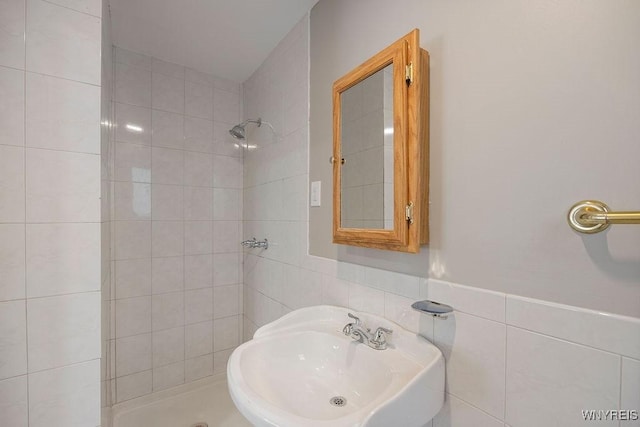 bathroom featuring tile walls, a tile shower, and sink