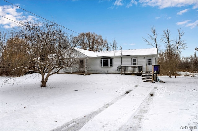 snow covered rear of property with a deck