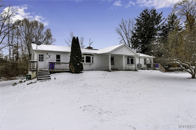 snow covered rear of property with a wooden deck