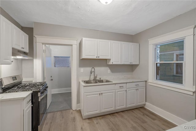 kitchen with sink, light hardwood / wood-style flooring, white cabinetry, and stainless steel gas range