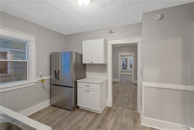 kitchen with white cabinets, light wood-type flooring, and stainless steel fridge with ice dispenser